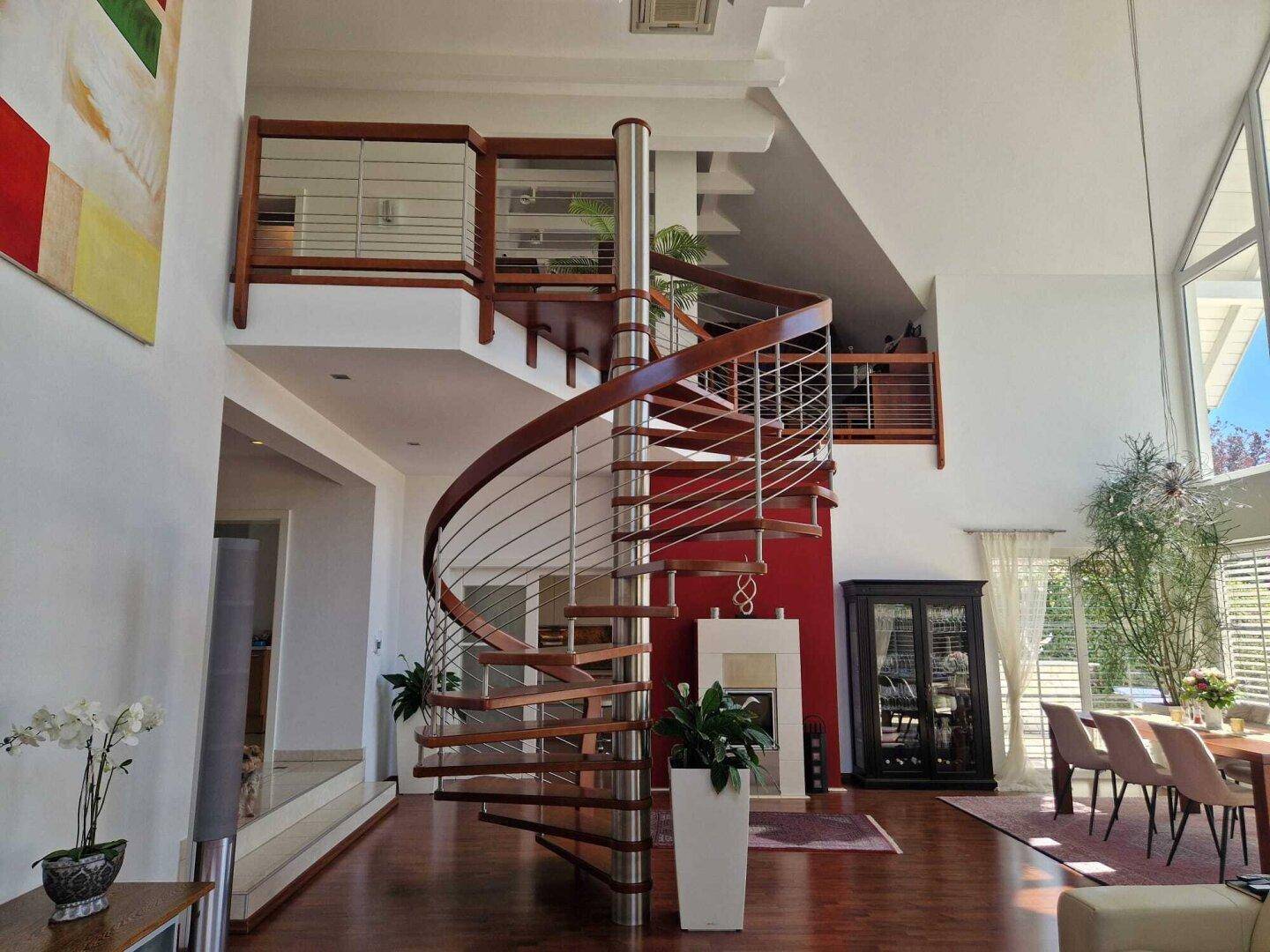 Großzügiger Wohnbereich mit Wendeltreppe, Kamin und hohen Fenstern für viel Licht.