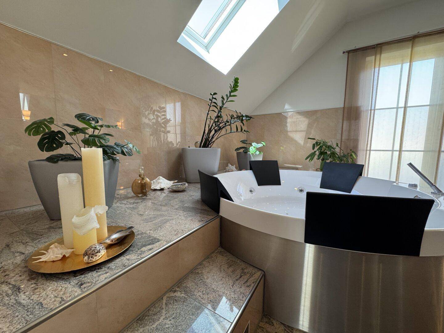 Detailansicht des Whirlpools im Badezimmer mit Kerzen und Pflanzen, unter einem Dachfenster.