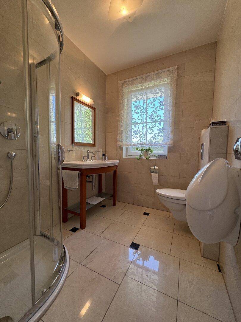 Badezimmer mit Duschkabine, Waschtisch und Fenster für natürliche Belüftung.