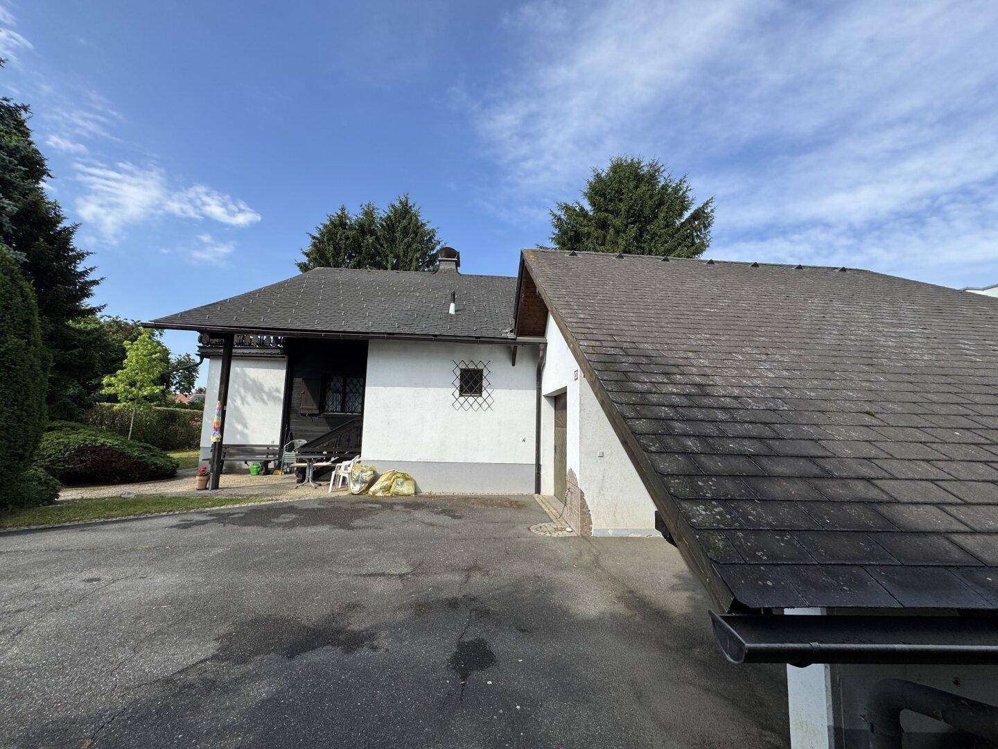 Seitenansicht des Hauses mit Garage und Dachflächen unter blauem Himmel.