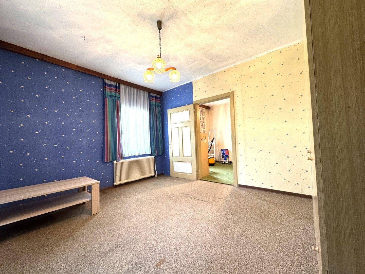 Schlafzimmer mit gemusterter Tapete, Teppichboden und Fenster, bereit zur individuellen Gestaltung.