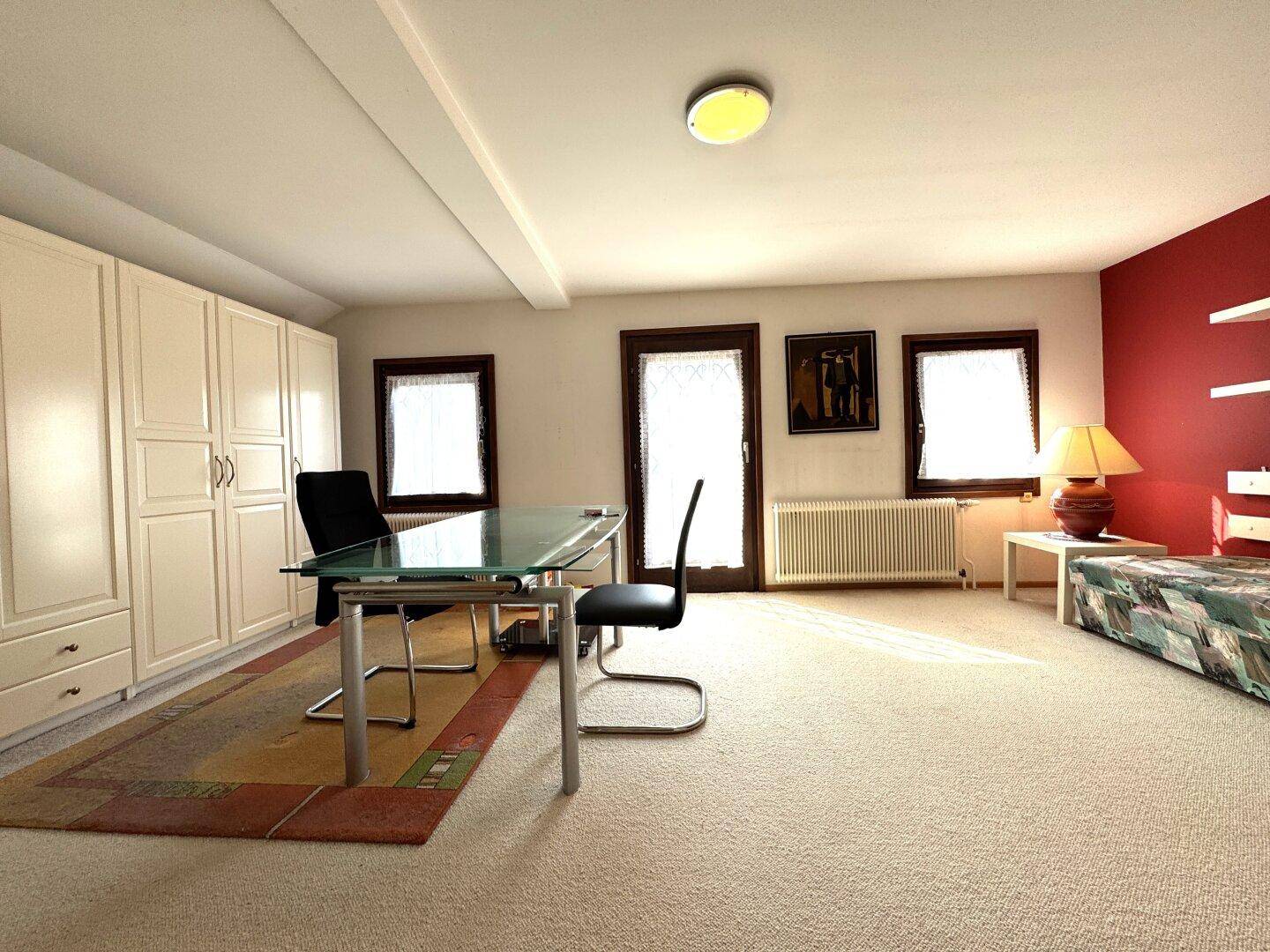 Geräumiger Arbeitsbereich mit Einbauschränken, Teppichboden und viel Tageslicht, ideal für Home-Office.