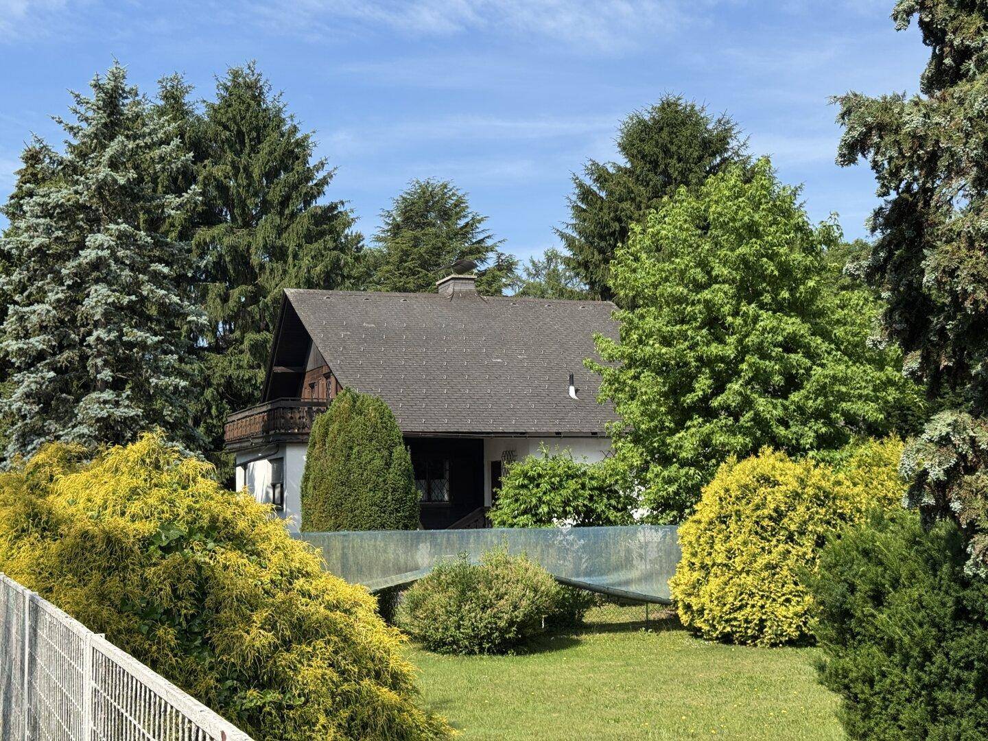Haus umgeben von üppigem Grün und Bäumen unter klarem Himmel, bietet viel Privatsphäre.