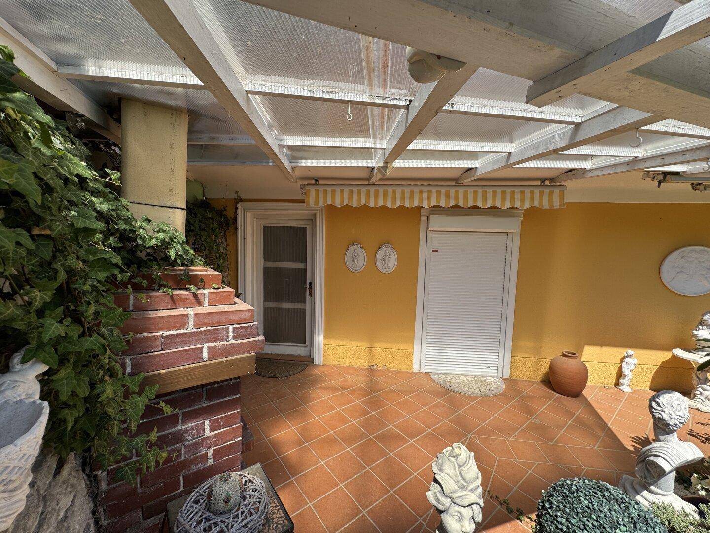 Überdachte Terrasse mit rustikalem Außenkamin und mediterranem Flair.
