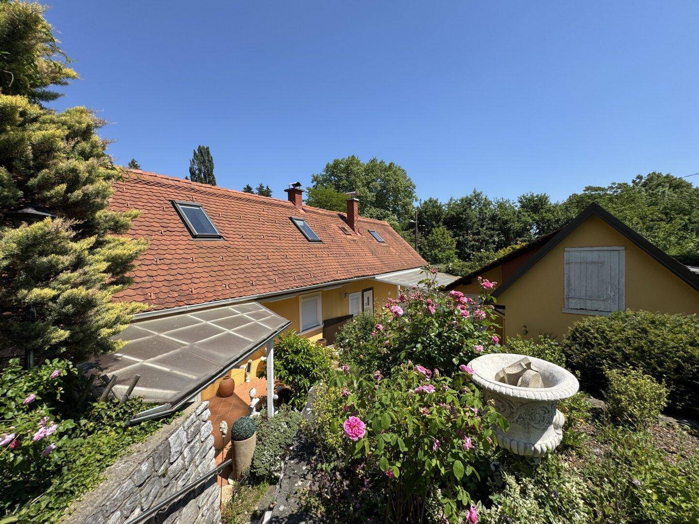 Weitläufiger Garten mit blühenden Rosen und Blick auf das charmante Wohnhaus.