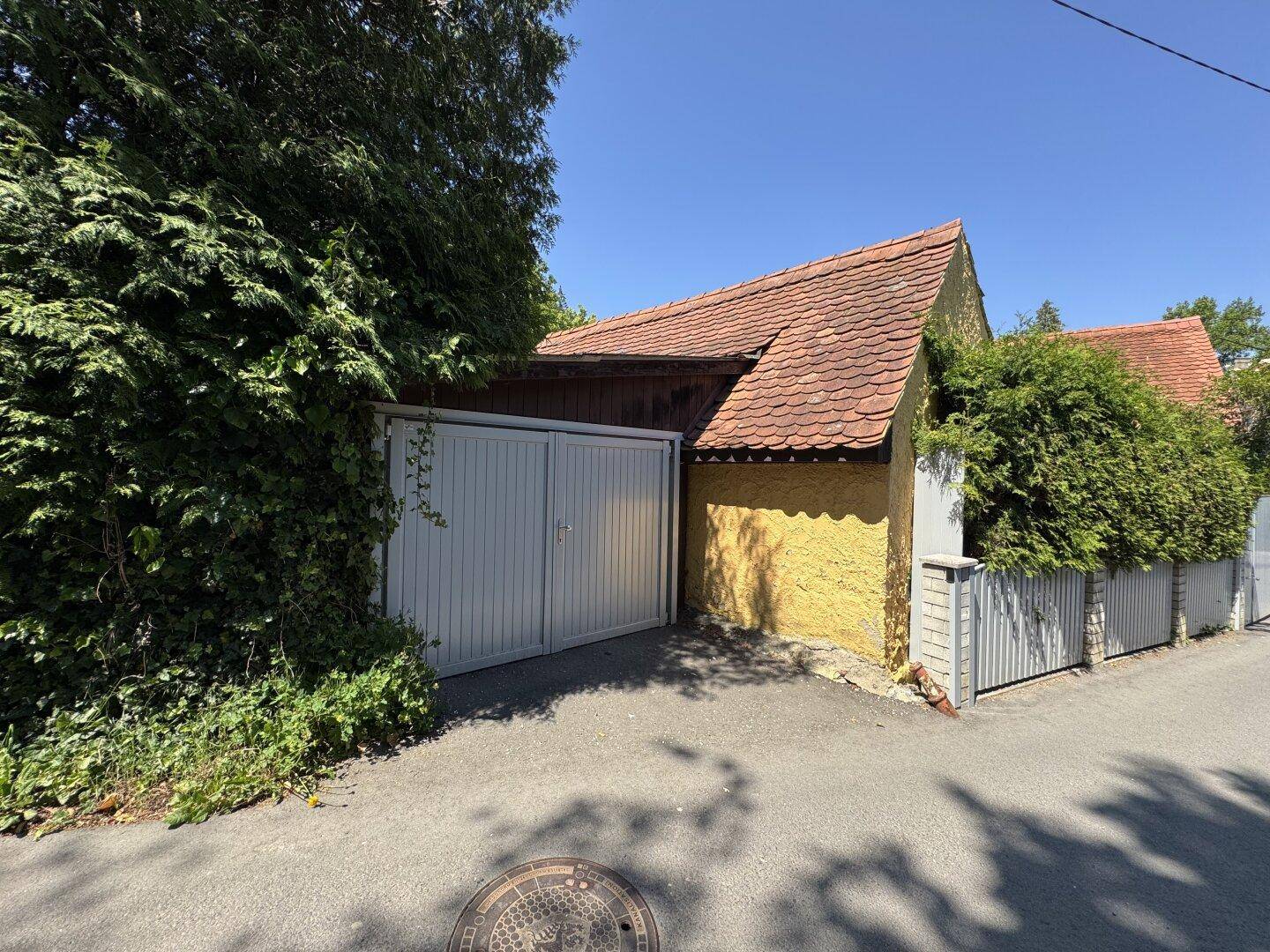 Garagenzufahrt mit Doppeltor und angrenzendem Nebengebäude.
