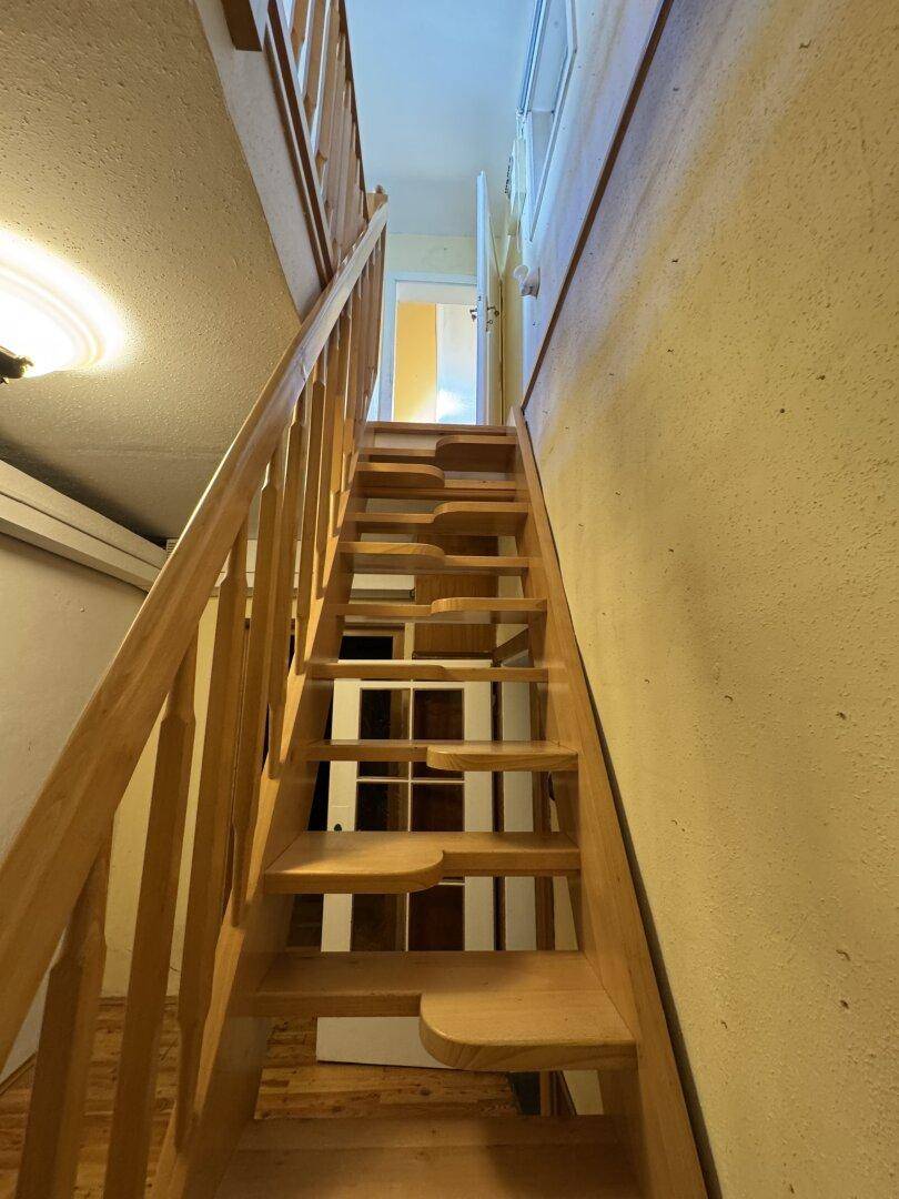 Helle Holztreppe führt in die oberen Stockwerke des Hauses.