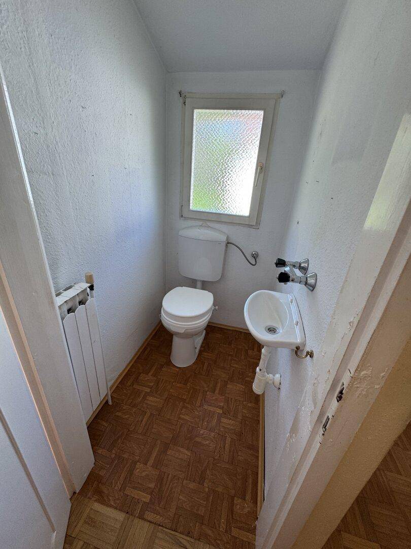 Kleines Gäste-WC mit Fenster, Toilette und Handwaschbecken.