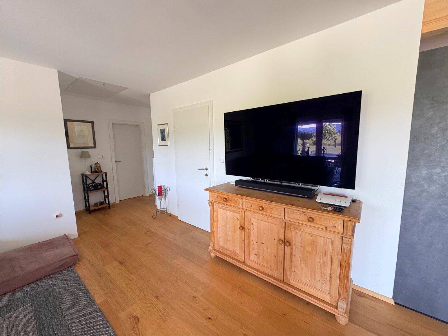 Heller Flur mit Holzboden und einem traditionellen Holzschrank unter dem Fernseher.