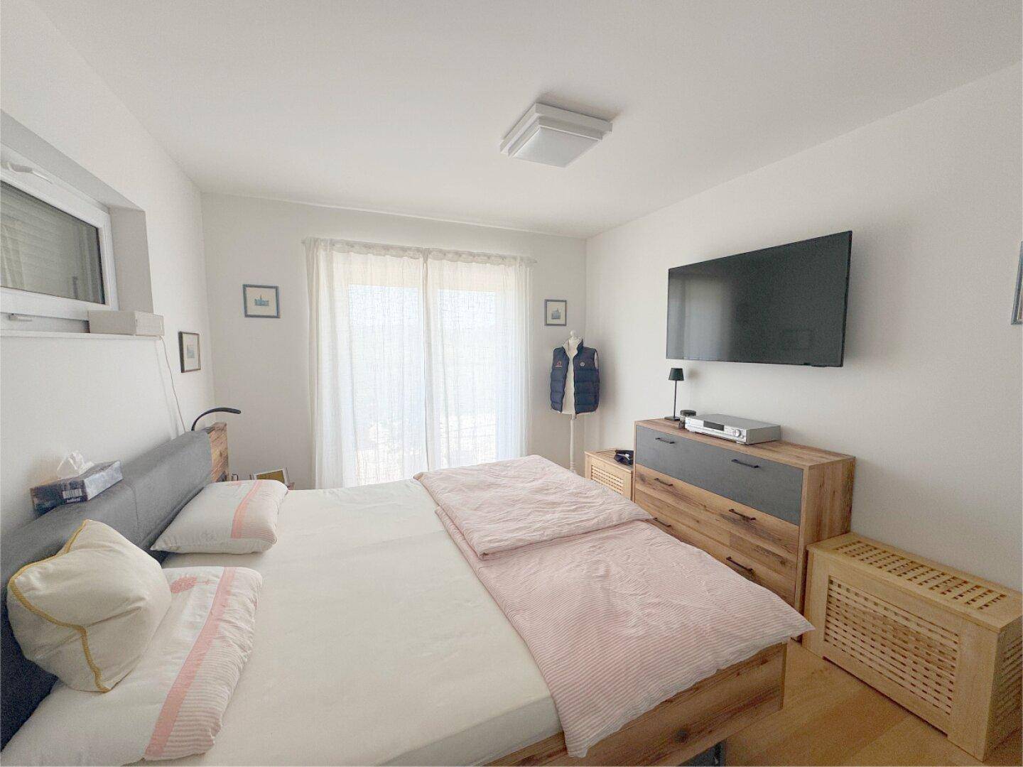 Gemütliches Schlafzimmer mit Doppelbett, Holzboden und Fenster mit Blick nach draußen.