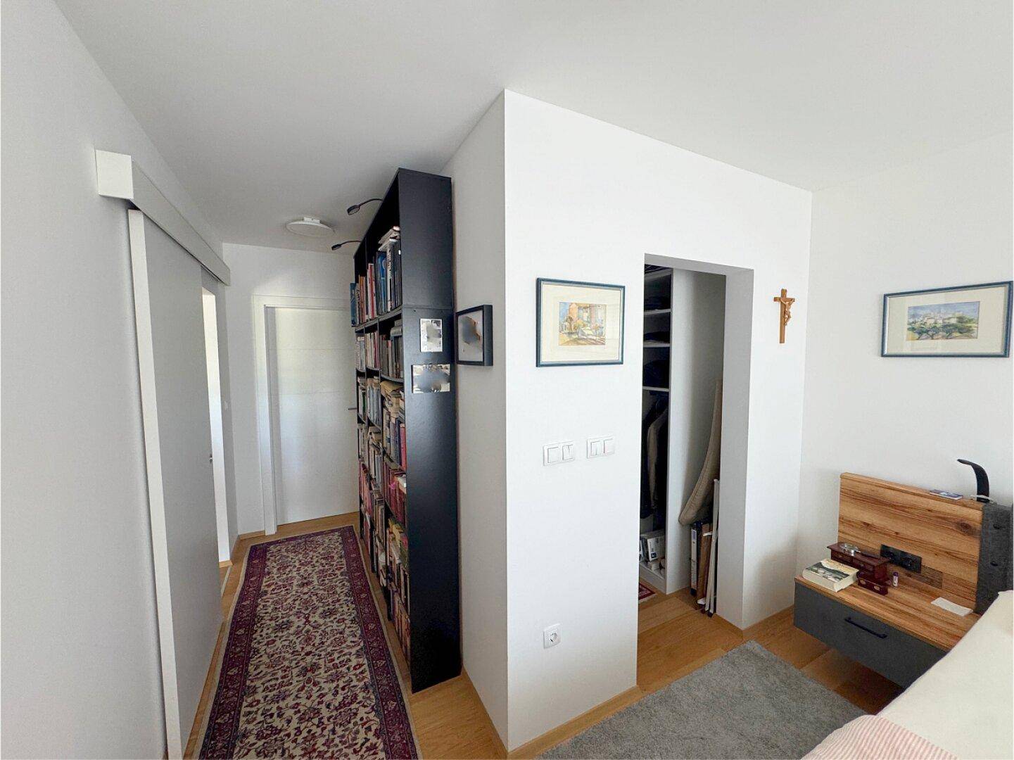 Schlafzimmer mit integriertem Bücherregal und Zugang zu einem begehbaren Kleiderschrank.