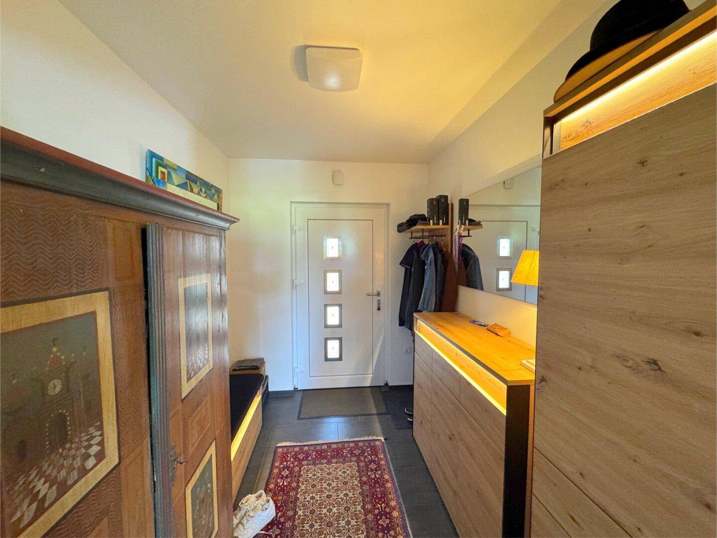 Eingangsbereich mit Garderobe, Spiegel und traditionellem Holzschrank.
