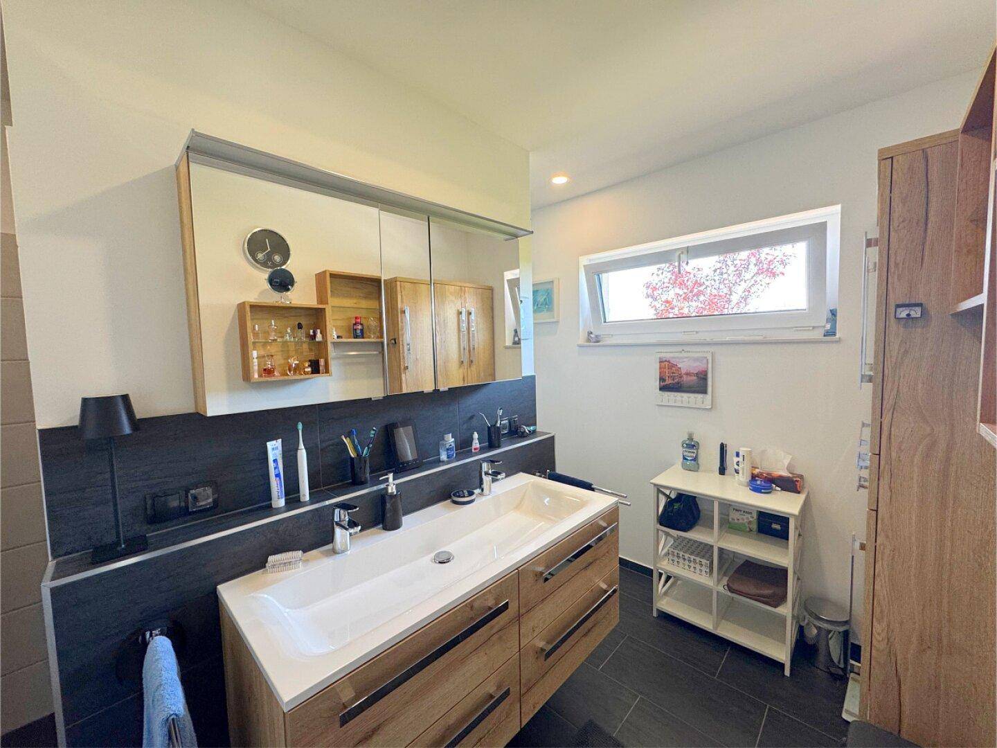 Modernes Badezimmer mit Doppelwaschbecken, Spiegelschrank und Holzmöbeln.