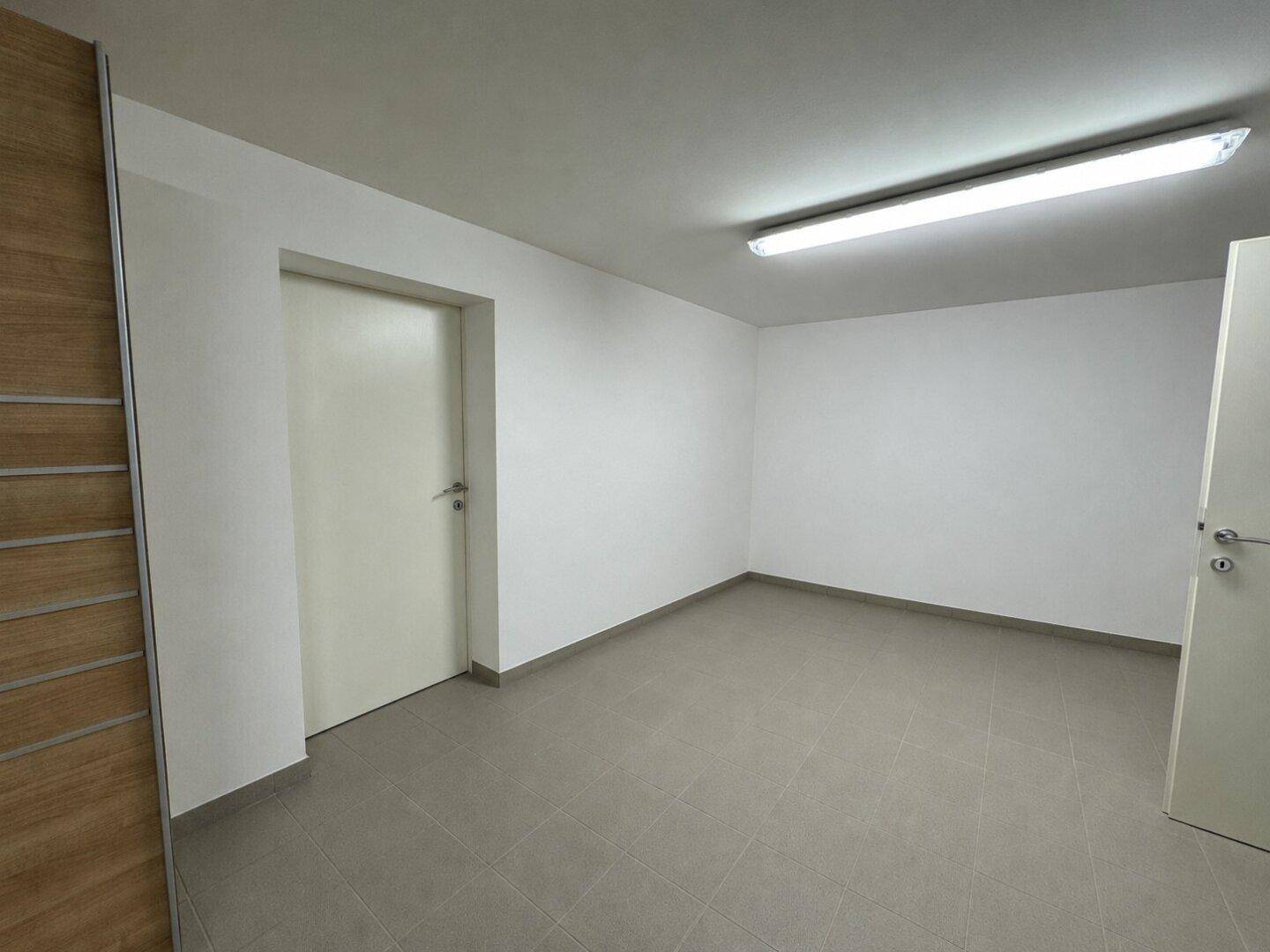 Leerer Abstellraum im Untergeschoss mit Fliesenboden und weiß gestrichenen Wänden.