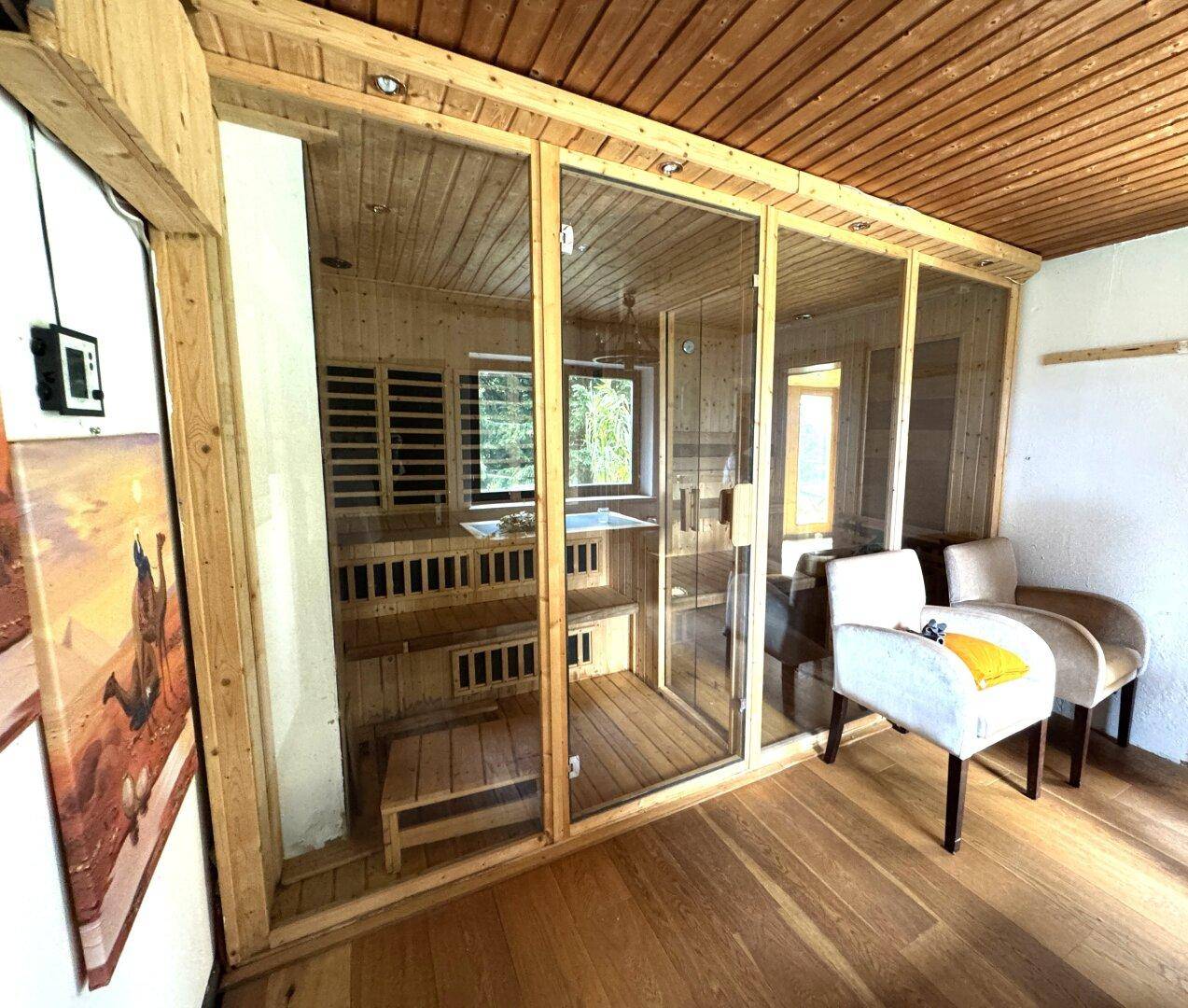 Geräumige Sauna mit Holzbänken und Glasfront im Wellnessbereich des Hauses.