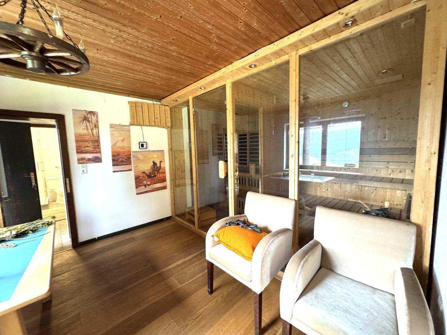 Entspannungsbereich mit Sauna, bequemen Sesseln und Holzboden, ideal zum Wohlfühlen.