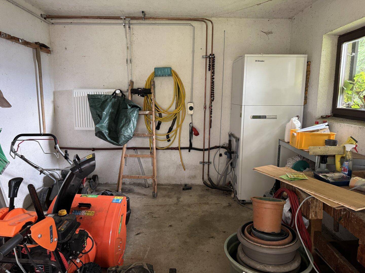 Praktischer Hauswirtschaftsraum mit Heizungsanlage, Werkzeugen und Stauraum für Gartengeräte.
