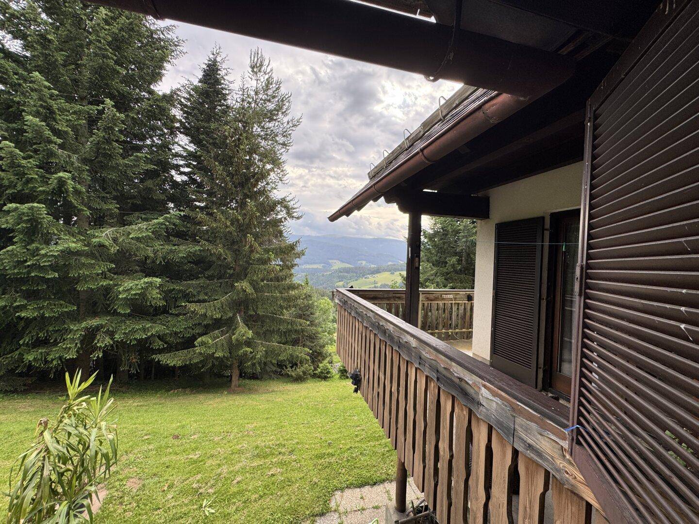 Balkon mit rustikalem Holzgeländer und Panoramablick auf die bewaldete Umgebung.