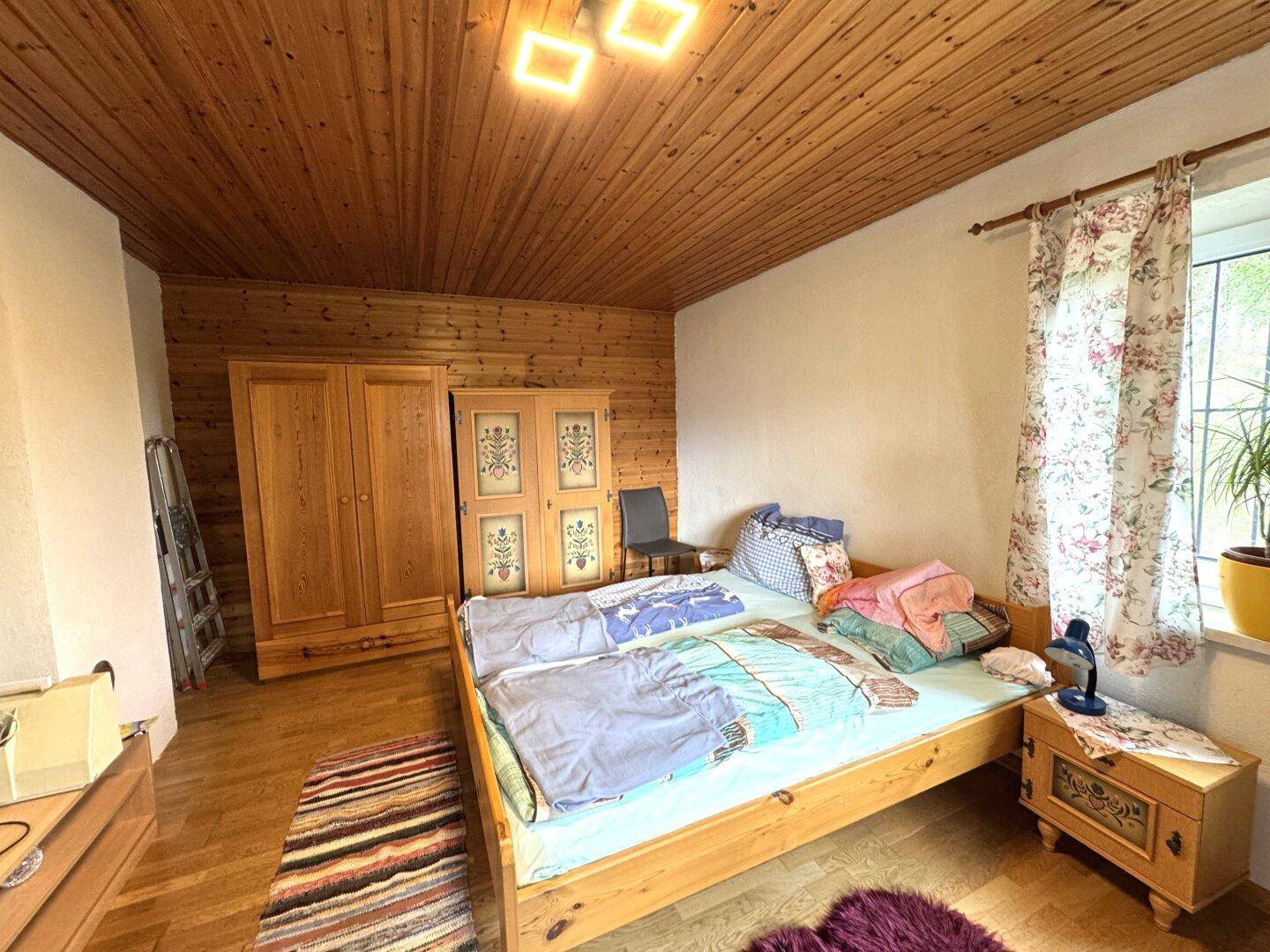 Schlafzimmer mit Doppelbett, Holzschrank und holzvertäfelter Decke, traditionell eingerichtet.