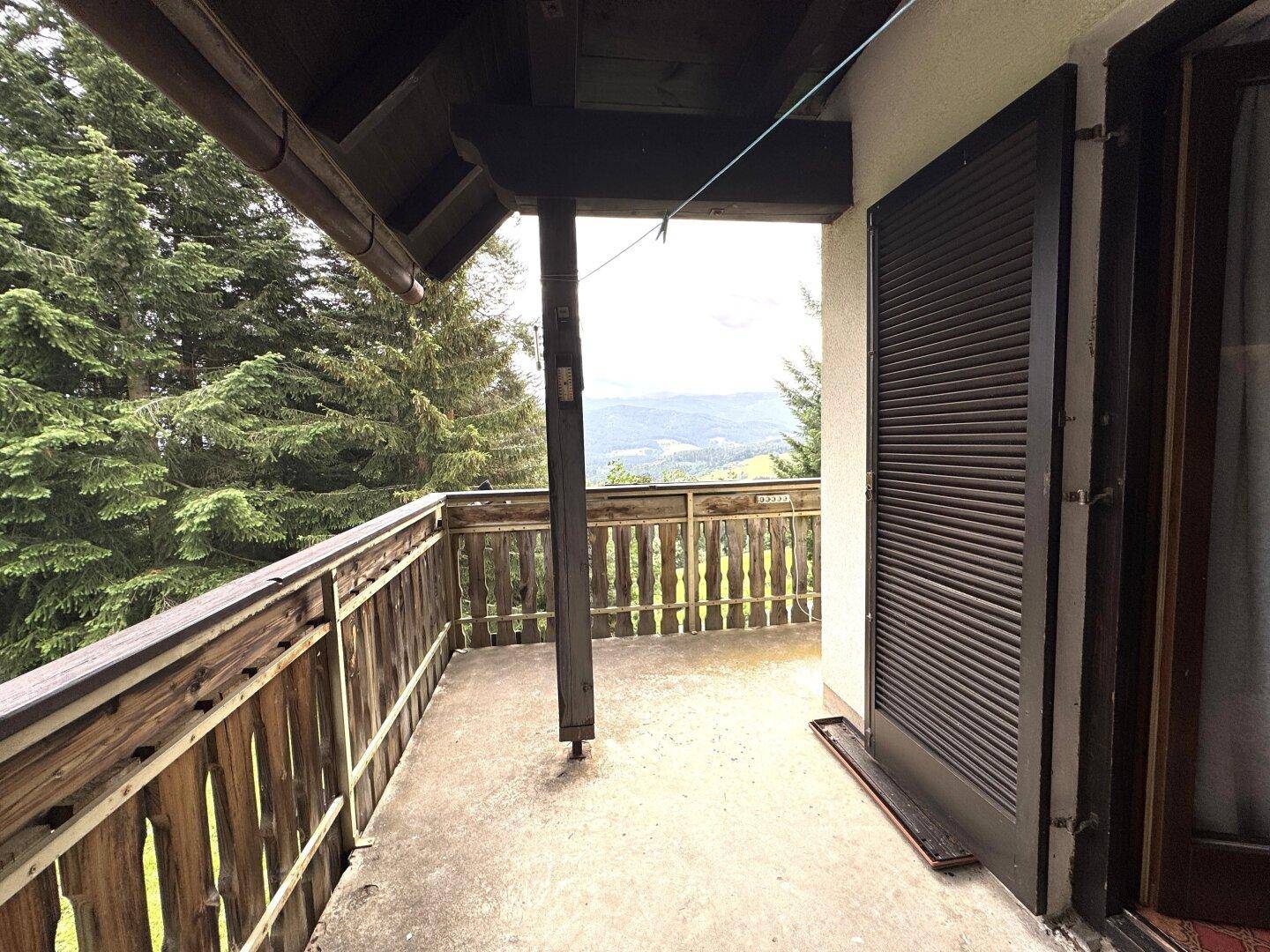 Geräumiger Holzbalkon mit weitem Blick über die grüne Hügellandschaft.