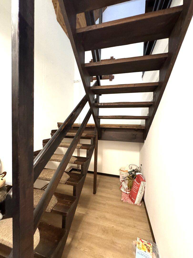 Dunkle Holztreppe mit Teppichstufen führt in die obere Etage des Hauses.