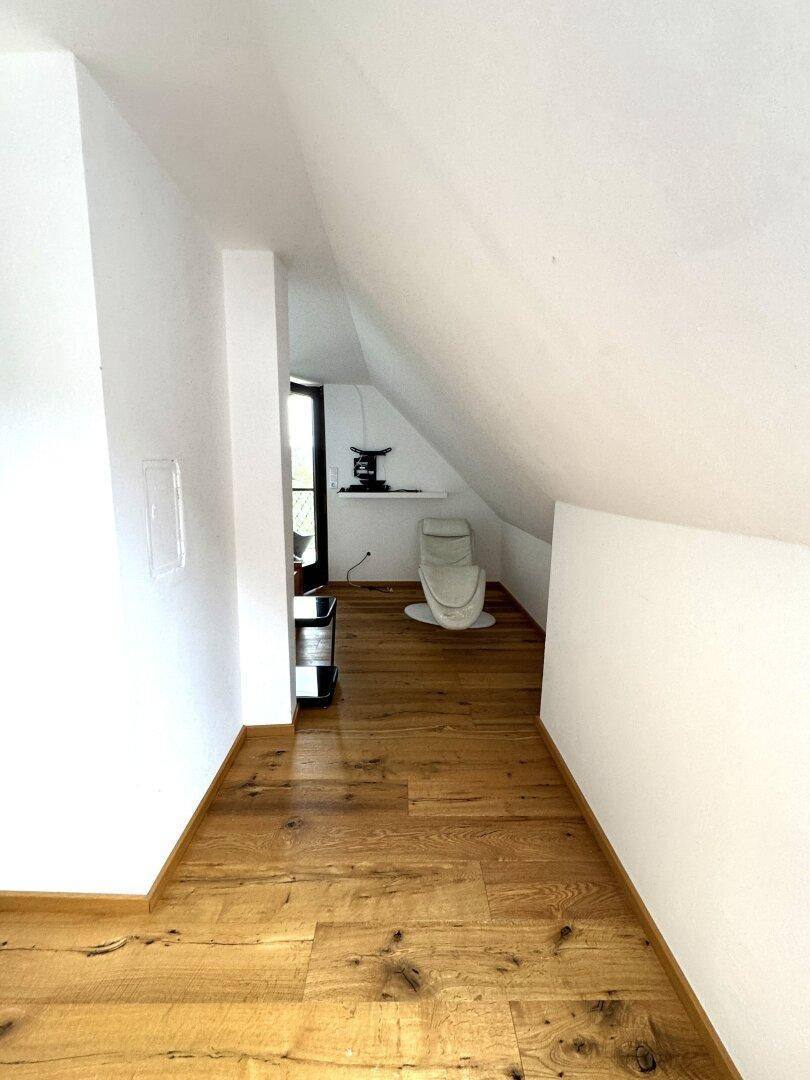 Heller Dachgeschossflur mit Holzboden und schräger Decke, führt zu weiteren Räumen.