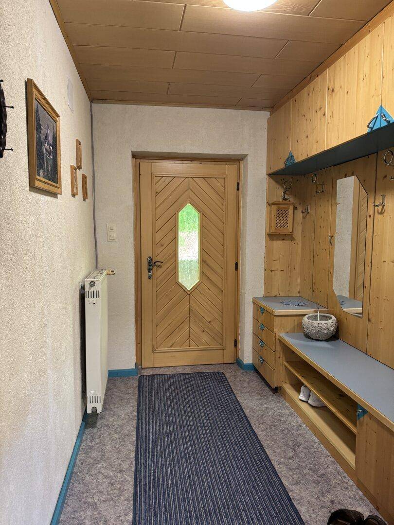 Gemütlicher Eingangsbereich mit Holzvertäfelung, Garderobe und Sitzbank.
