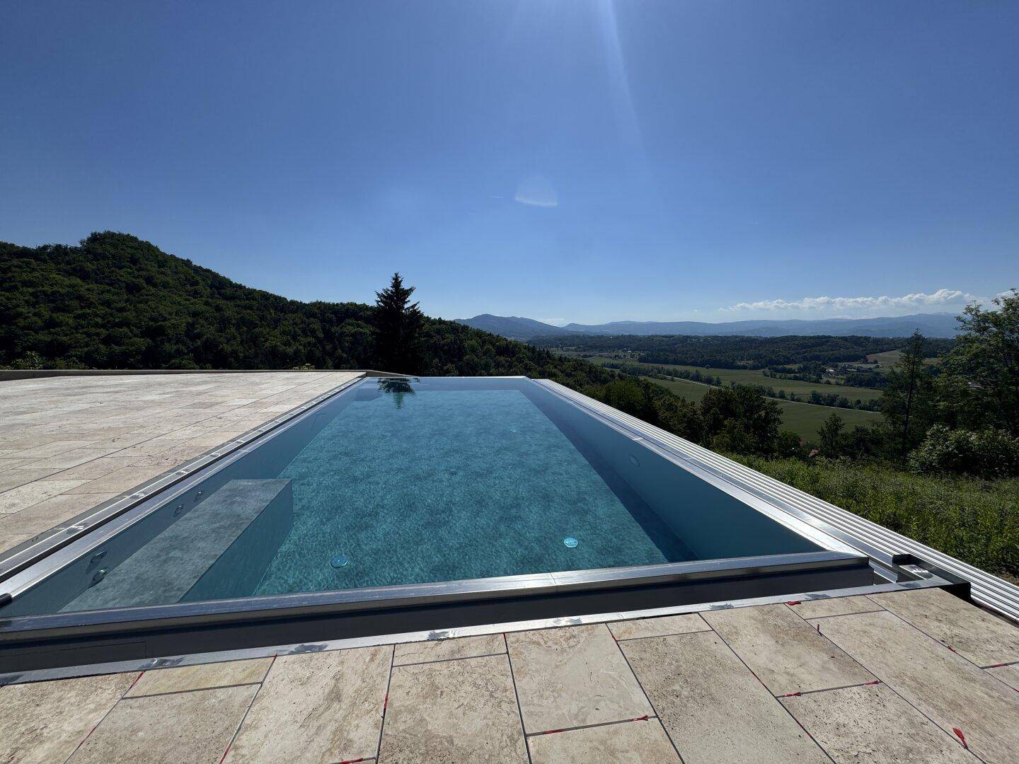 Infinity-Pool mit klarblauem Wasser und weitem Blick über die idyllische Landschaft.