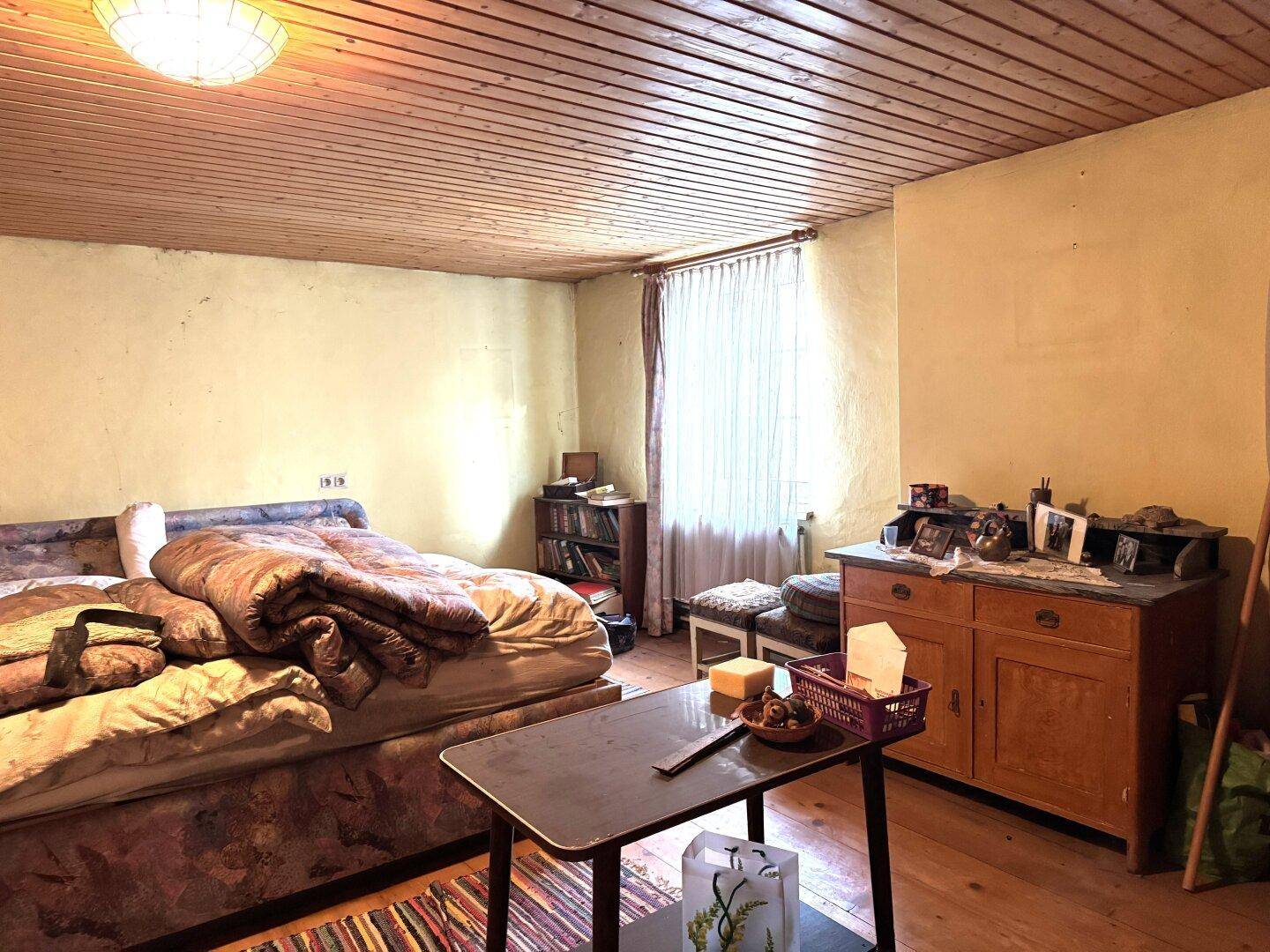 Schlafzimmer mit Holzdielenboden, Holzdecke und einem Bett, eingerichtet im Vintage-Stil.