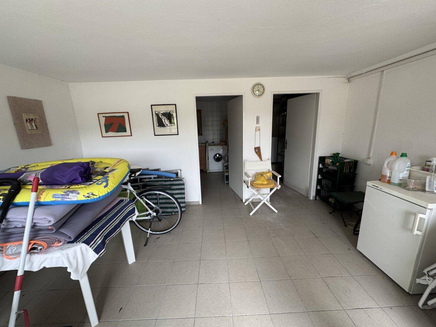 Geräumiger Kellerraum mit Fliesenboden, Waschmaschine und viel Platz für Lagerung.