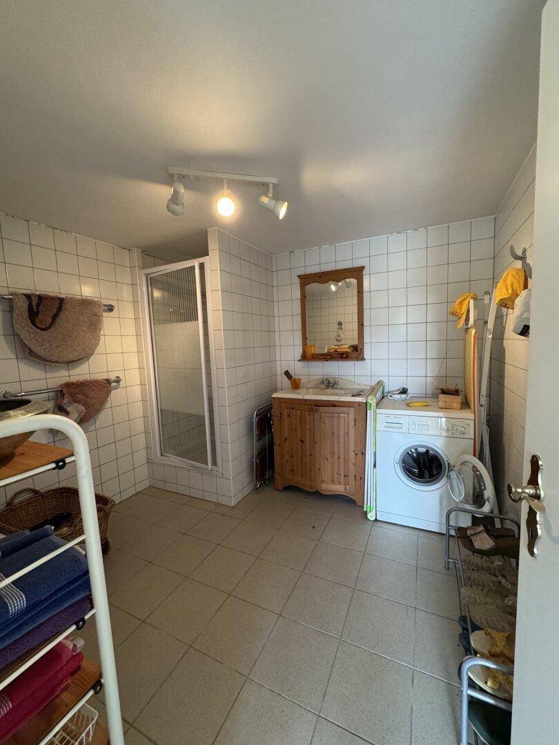 Funktionales Badezimmer im Keller mit Duschkabine, Waschmaschine und Holzwaschtisch.