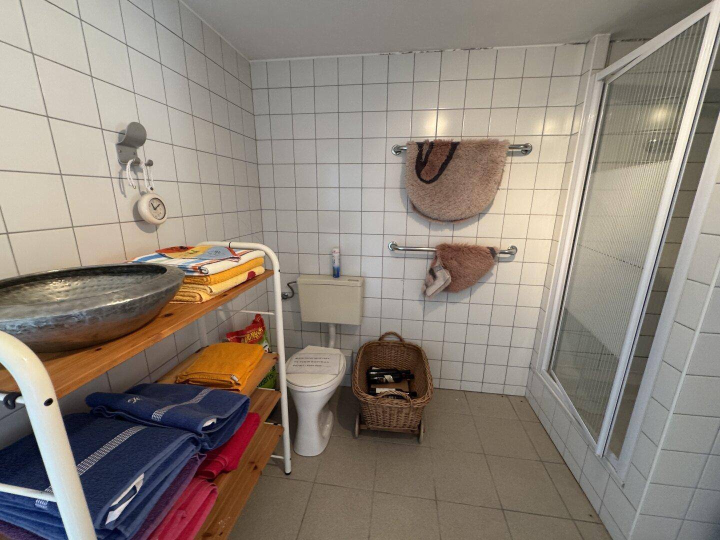 Einfaches Badezimmer im Keller mit Duschkabine, WC und Fliesen an Wänden und Boden.