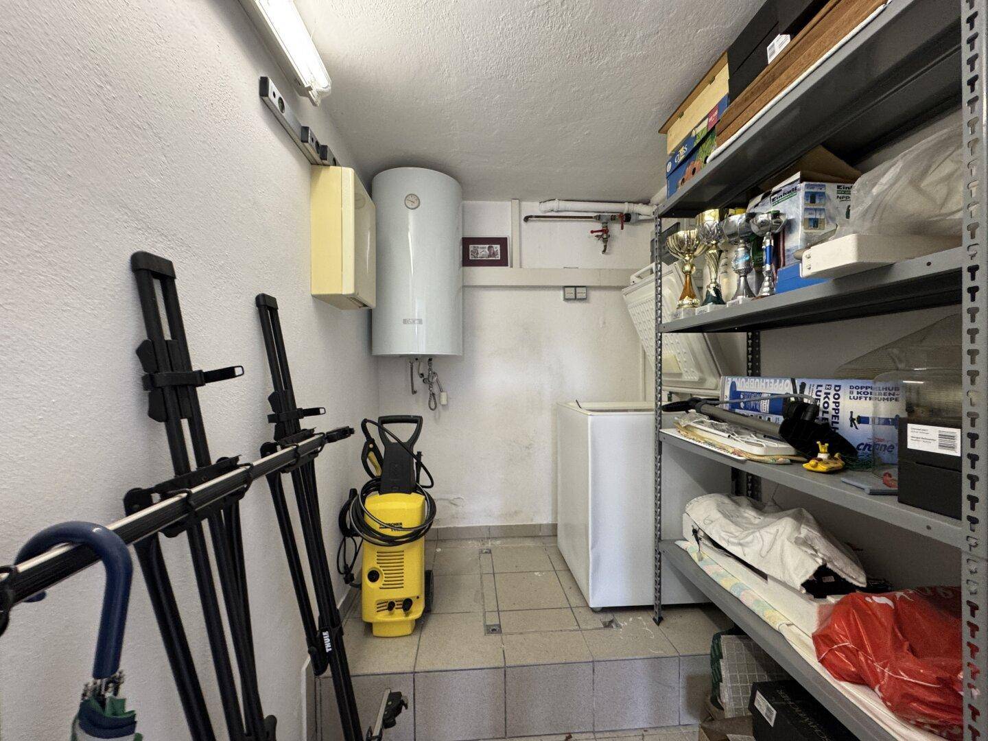 Kellerraum mit Regalen, Warmwasserboiler und Reinigungsgeräten, ideal als Abstellraum.