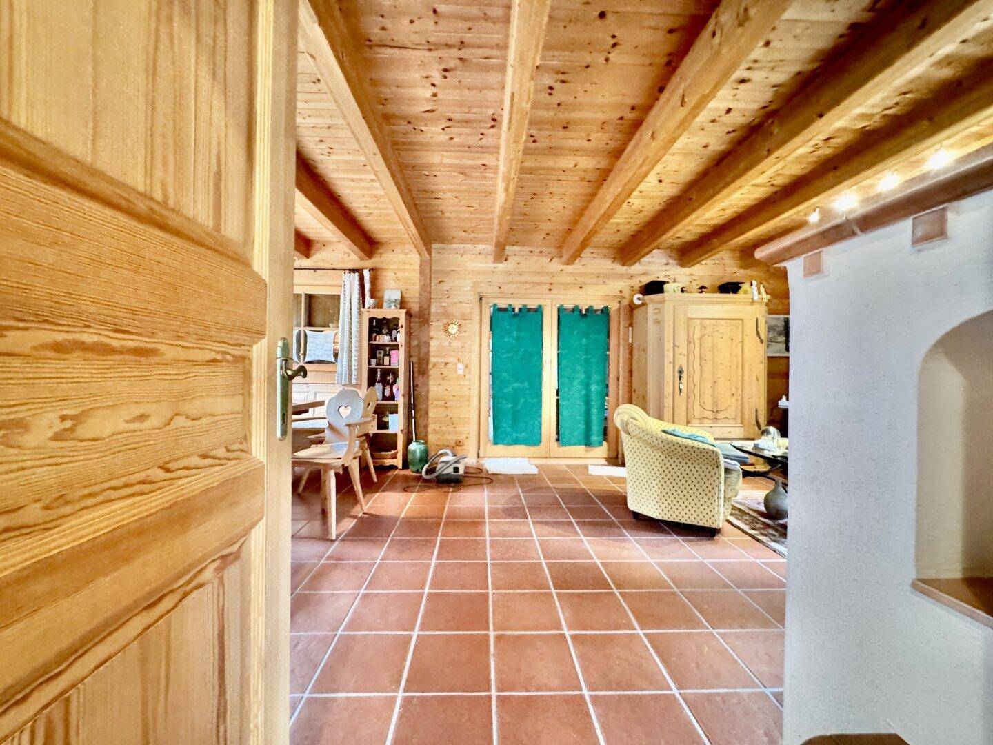 Rustikaler Wohnbereich mit Holzbalkendecke und Terrakottafliesen, einladend und traditionell gestaltet.