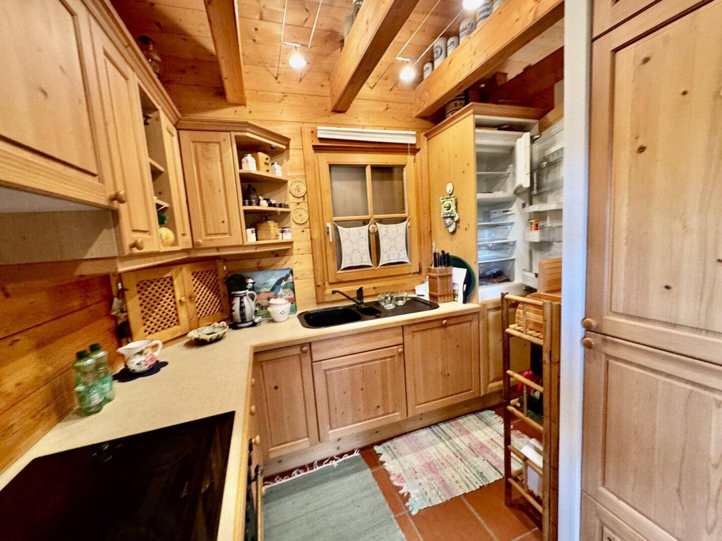Gemütliche Holzküche mit Einbauschränken, Spüle und Kühlschrank, im traditionellen Stil gehalten.