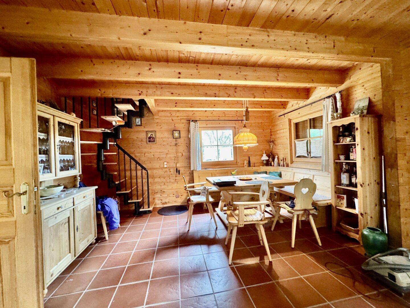 Rustikaler Essbereich mit Holztisch und Eckbank, umgeben von Holzvertäfelung und Terrakottafliesen.