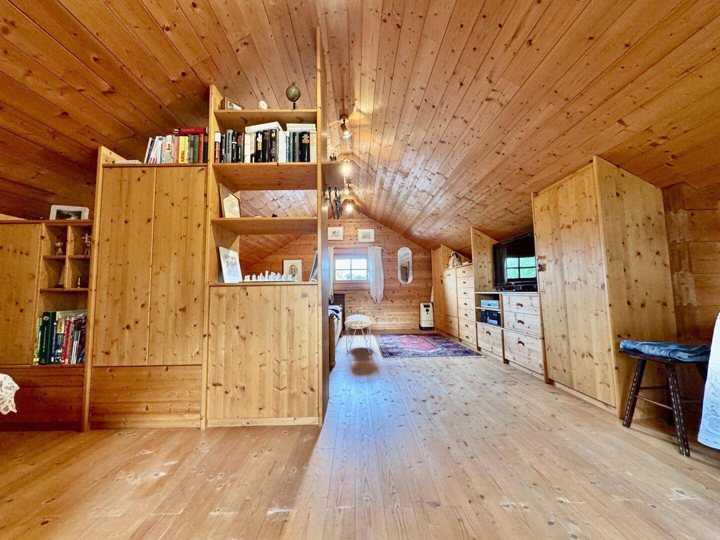 Geräumiges Dachgeschosszimmer mit Holzvertäfelung, Einbauschränken und viel Stauraum.