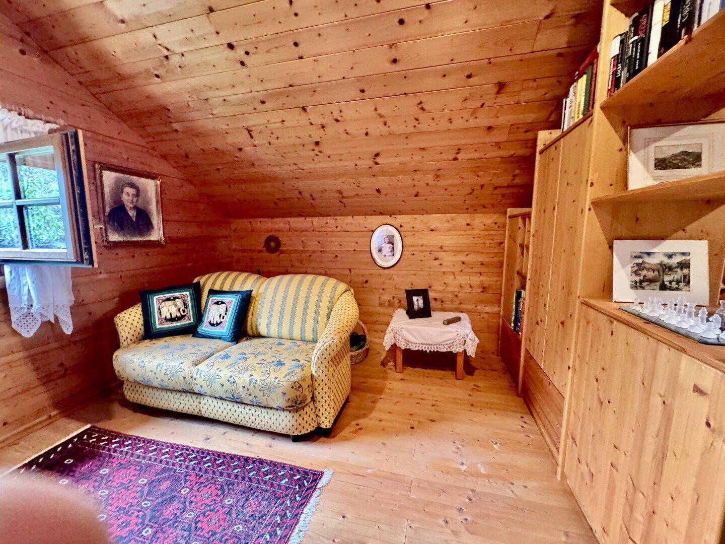 Gemütliches Schlafzimmer im Dachgeschoss mit Holzvertäfelung, Dachschräge und Teppichboden.