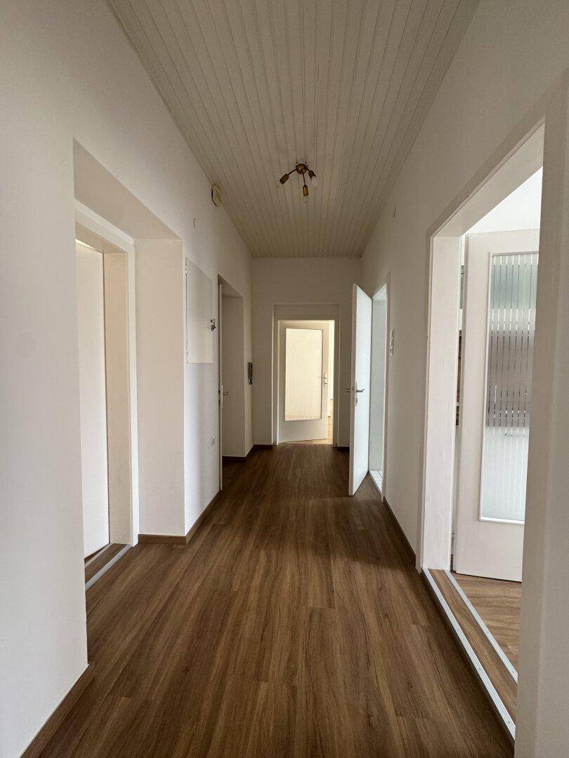 Langer Flur mit Holzdielenboden und mehreren Türen, der verschiedene Räume verbindet.