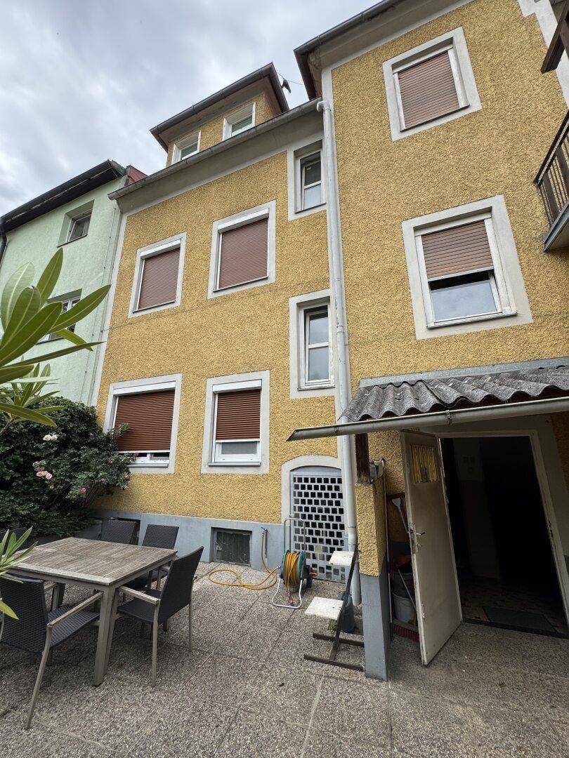 Hinterhof-Terrasse mit Gartenmöbeln und Blick auf die Rückseite des Gebäudes.
