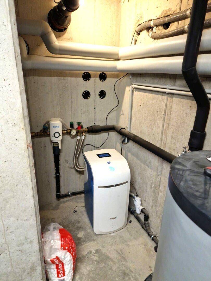 Technikraum im Keller mit Wasserenthärtungsanlage und Rohrleitungen.