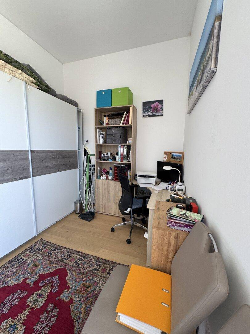 Funktionales Arbeitszimmer mit Schreibtisch, Bürostuhl und einem großen Kleiderschrank.