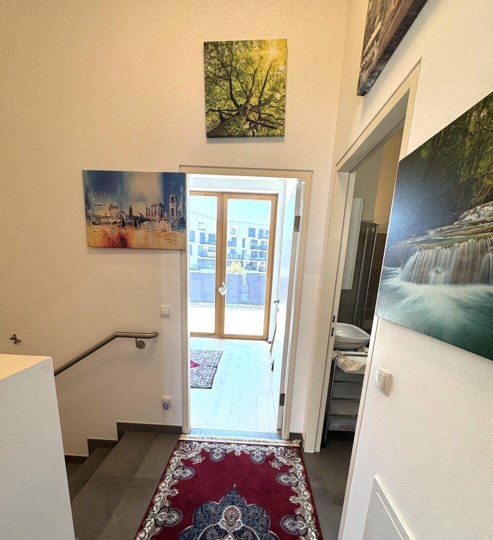 Unterer Bereich des Treppenhauses mit Blick auf eine Tür, die nach draußen führt.