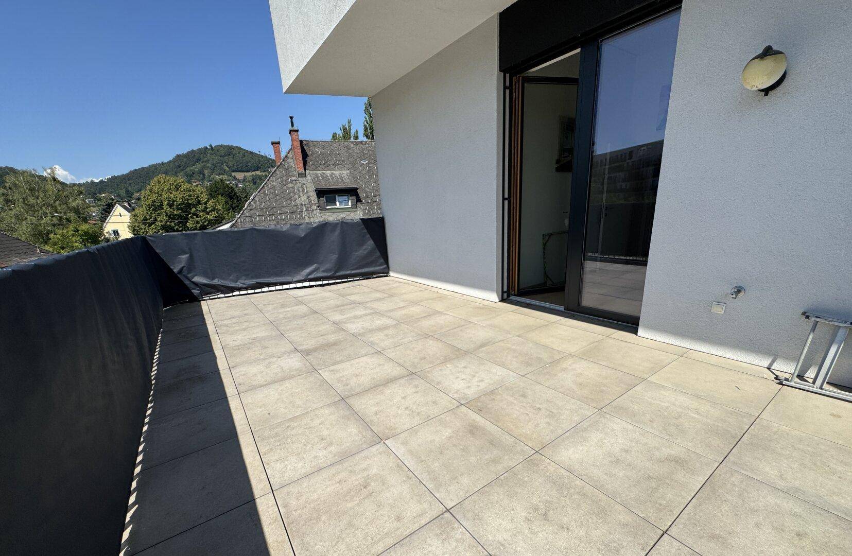 Geräumiger Balkon mit Fliesenboden und Blick auf die umliegende Wohngegend.