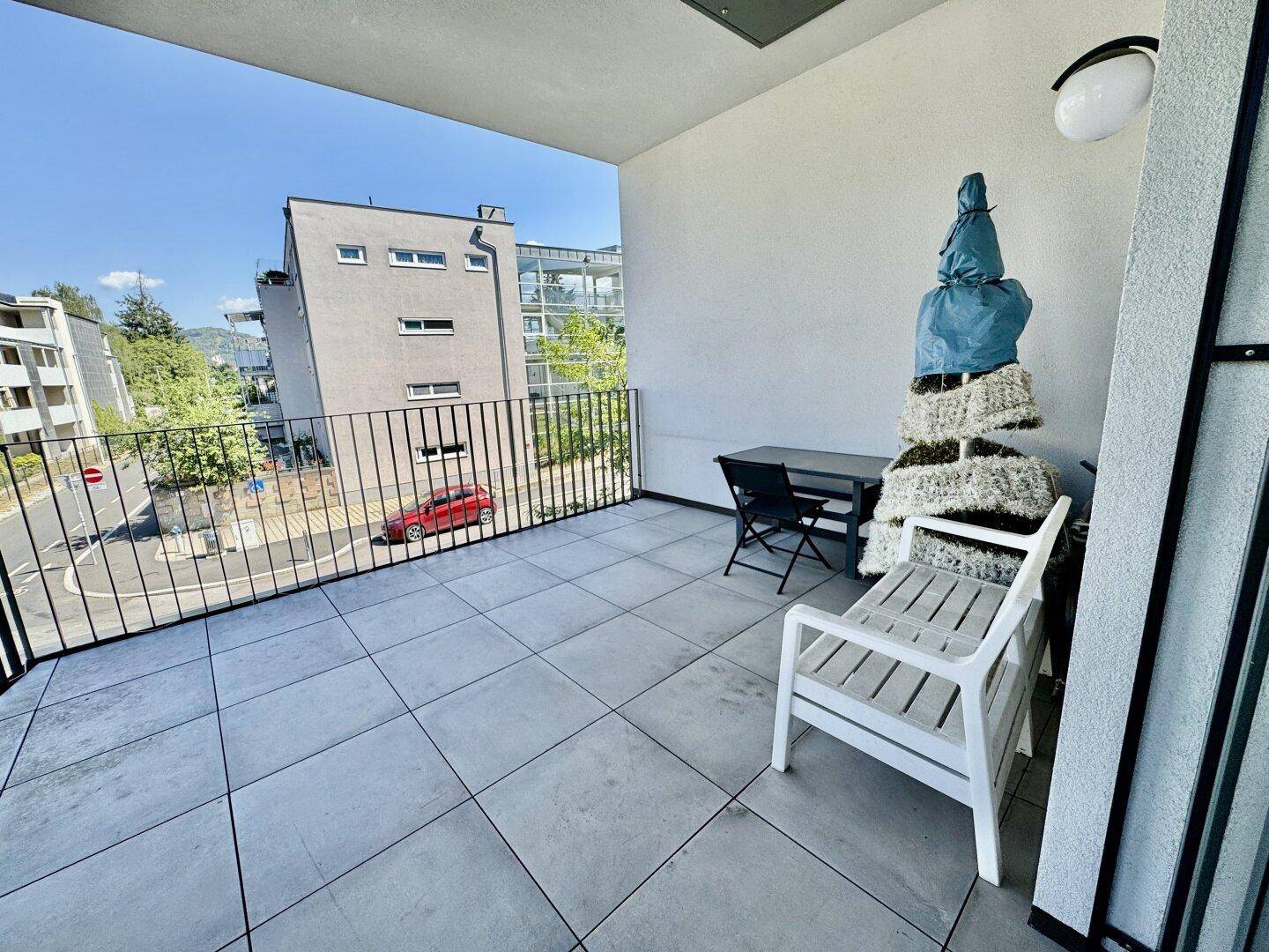 Balkon mit Sitzgelegenheiten und Blick auf die Straße sowie die umliegenden Gebäude.