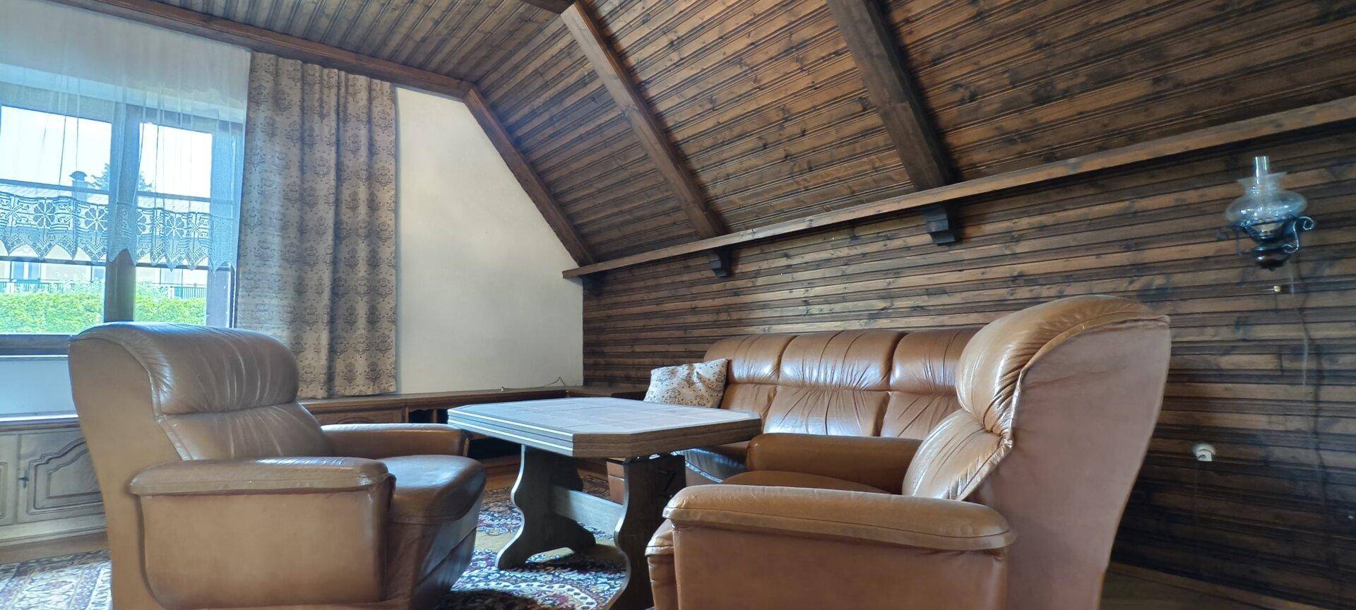 Wohnbereich unter der Dachschräge mit Ledersofas und Holztisch.
