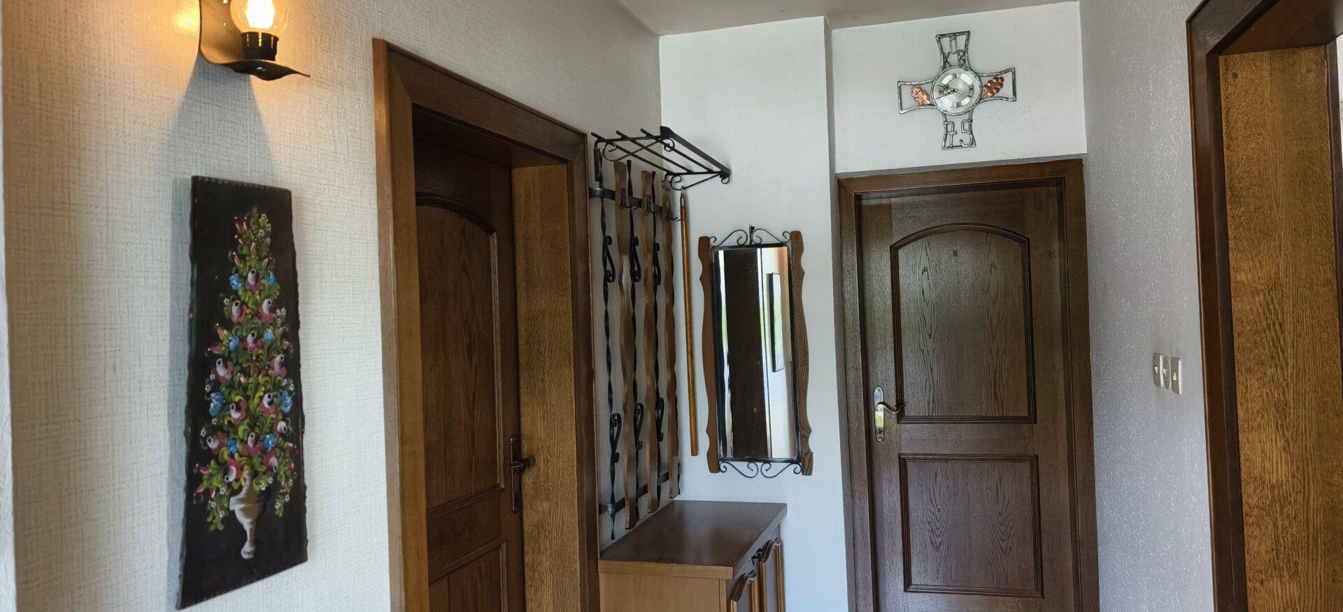 Flur mit Holztüren, Garderobe und einem dekorativen Spiegel.