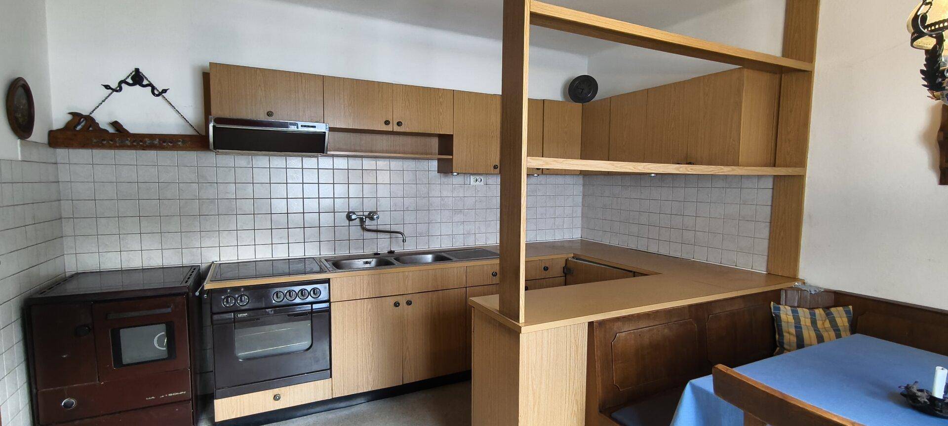 Rustikale Küche mit Holzschränken, Fliesenrückwand und integriertem Essbereich.