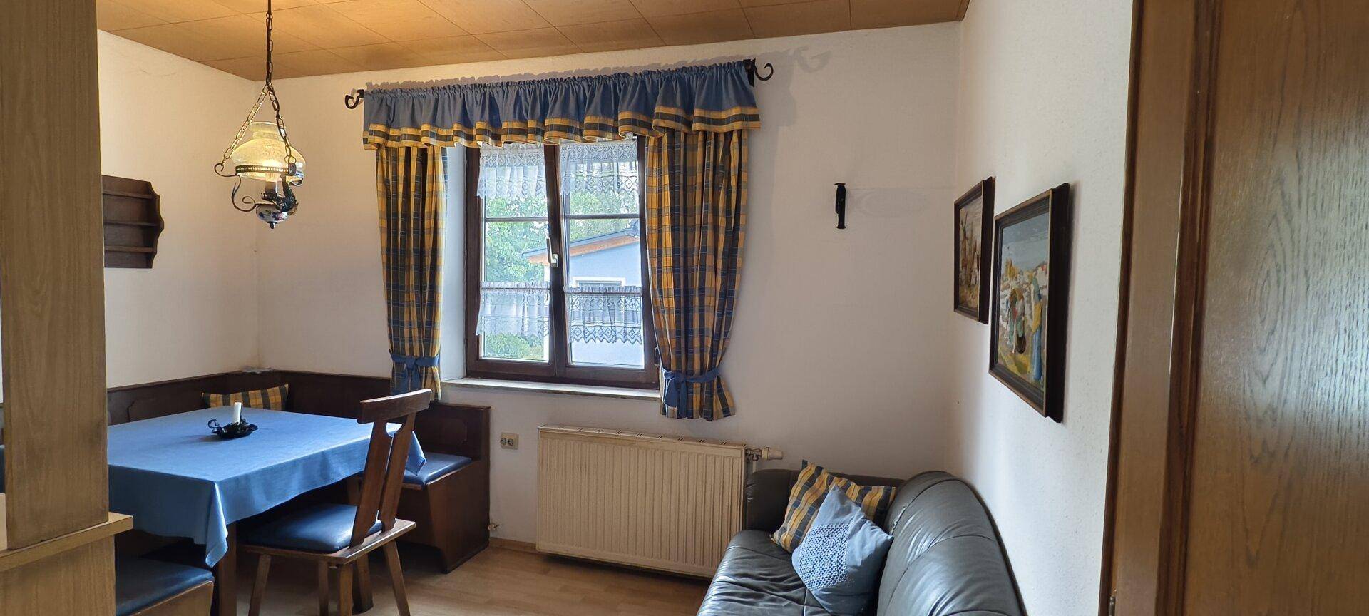 Essbereich mit Eckbank, Holztisch und traditionellen Vorhängen.