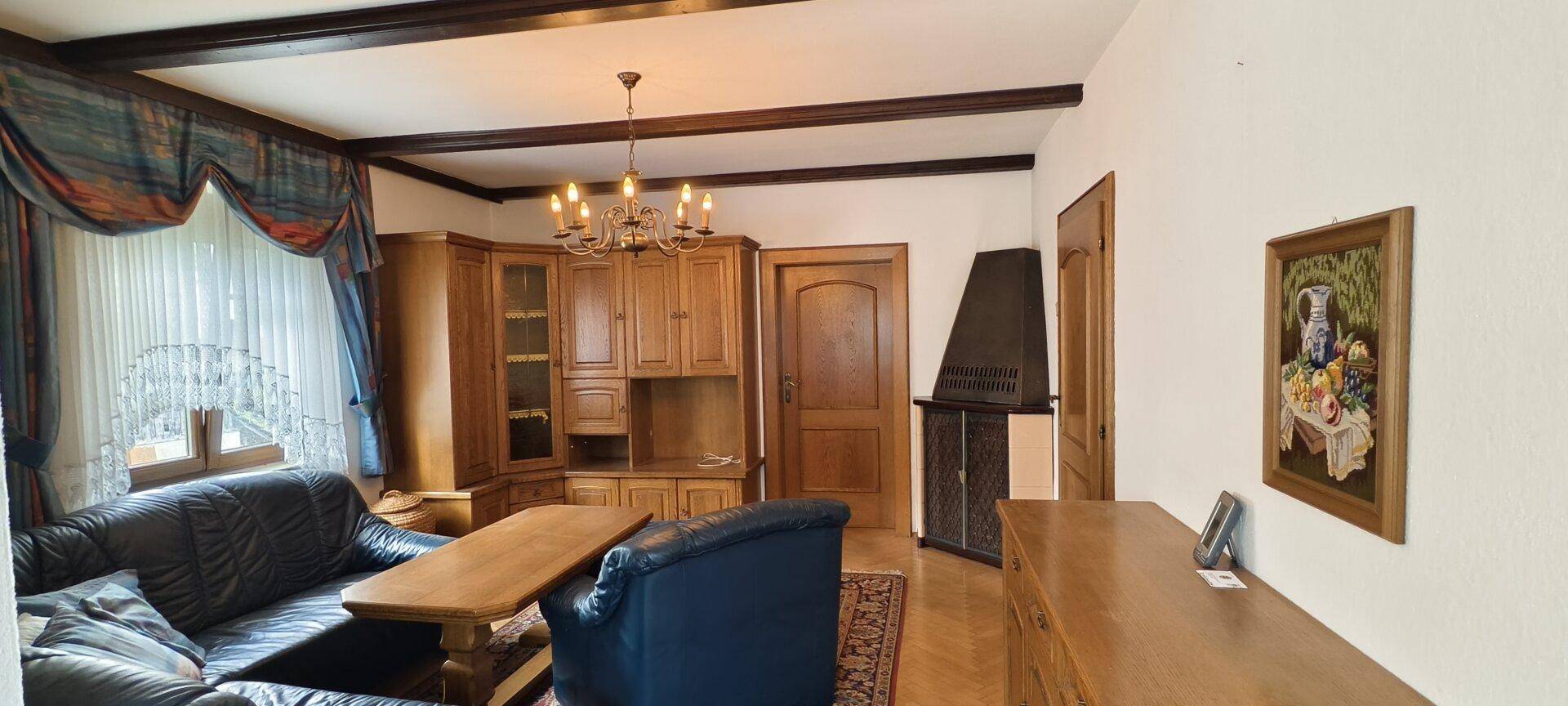 Geräumiges Wohnzimmer mit Holzbalken, Ledersofas und traditioneller Einrichtung.